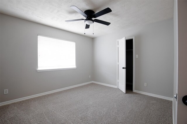 unfurnished bedroom featuring carpet floors, a ceiling fan, a textured ceiling, and baseboards