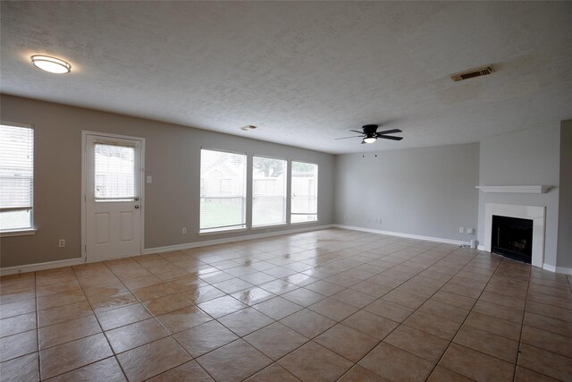 unfurnished living room with visible vents, plenty of natural light, ceiling fan, and tile patterned floors