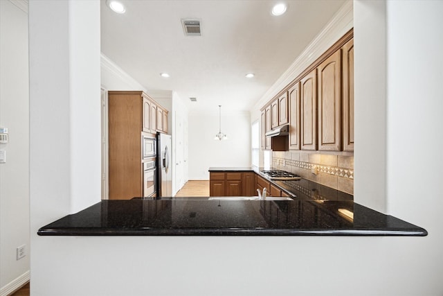 5309 Elm St, Houston, TX 77081 - kitchen with appliances with stainless steel finishes, a peninsula, under cabinet range hood, visible vents, and decorative backsplash