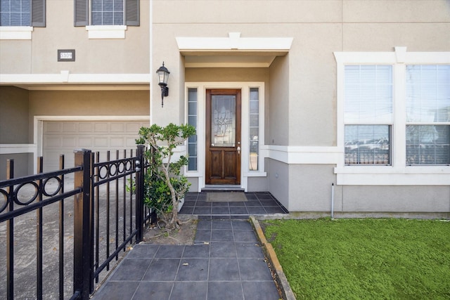 5309 Elm St, Houston, TX 77081 - view of exterior entry with stucco siding, an attached garage, and fence