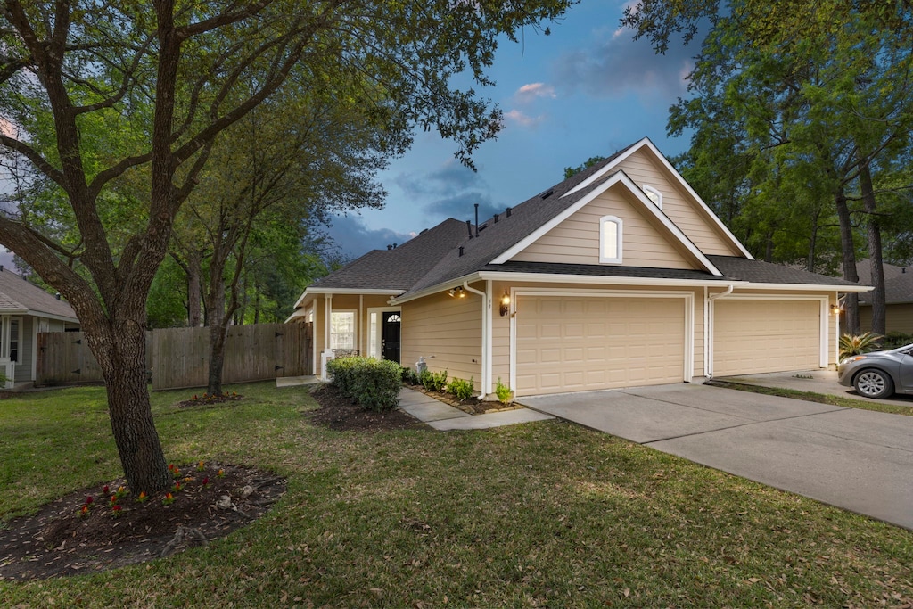 11 Trafalgar Pl, Conroe, TX 77384 - traditional-style home featuring fence, a garage, a front yard, roof with shingles, and driveway