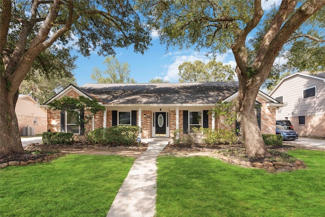 ranch-style home with brick siding, roof with shingles, central AC, and a front lawn