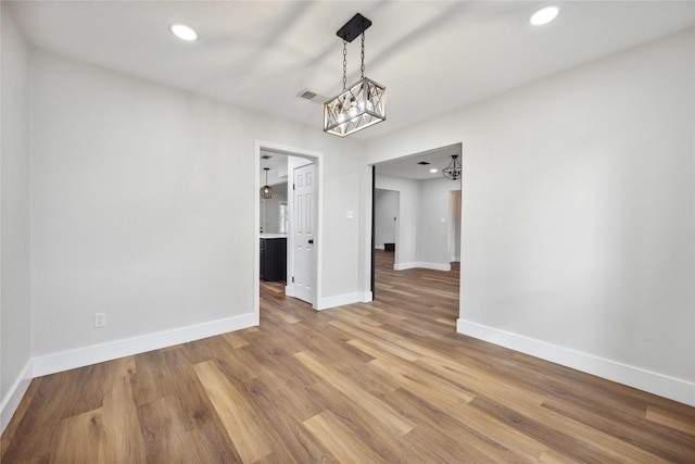 unfurnished dining area with a chandelier, light wood-type flooring, baseboards, visible vents, and recessed lighting