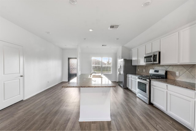 5135 Dunstable Manor Ln, Rosharon, TX 77583 - kitchen with stainless steel appliances, a sink, white cabinets, decorative backsplash, and an island with sink