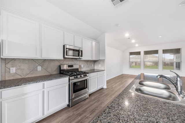 5135 Dunstable Manor Ln, Rosharon, TX 77583 - kitchen with appliances with stainless steel finishes, a sink, white cabinets, decorative backsplash, and vaulted ceiling