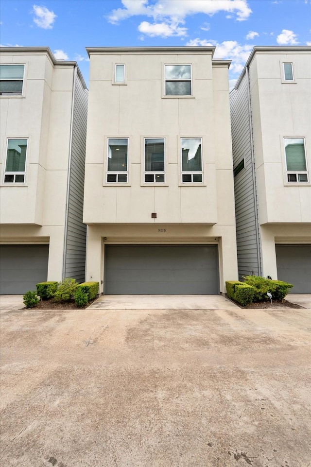 view of property featuring stucco siding, a garage, and concrete driveway