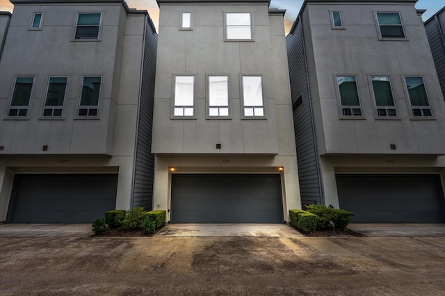 view of front facade featuring an attached garage, driveway, and stucco siding