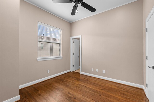 unfurnished bedroom with crown molding, wood finished floors, baseboards, and a ceiling fan
