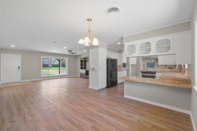 kitchen featuring open floor plan, stainless steel electric range, ceiling fan with notable chandelier, visible vents, and freestanding refrigerator