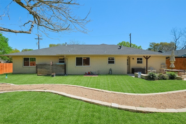 back of property with brick siding, fence, a shingled roof, and a yard