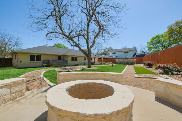 exterior space with an outdoor fire pit, a fenced backyard, brick siding, and a lawn