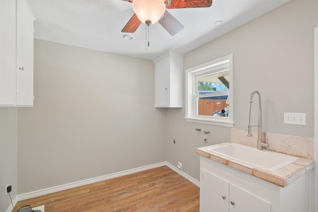 clothes washing area featuring washer hookup, baseboards, a sink, light wood-type flooring, and cabinet space