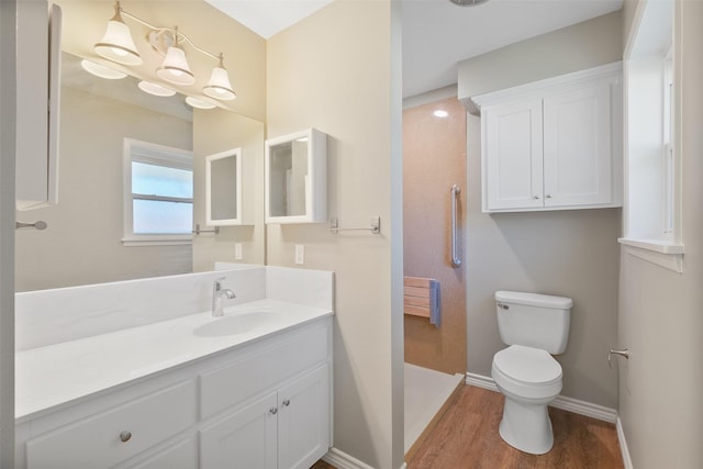 bathroom with walk in shower, baseboards, toilet, wood finished floors, and vanity