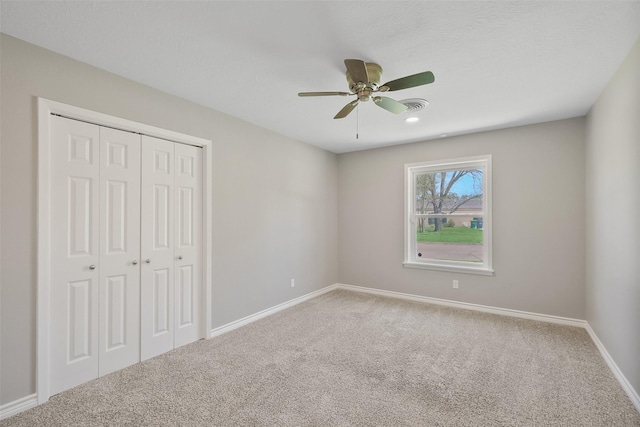 unfurnished bedroom featuring a closet, visible vents, baseboards, a ceiling fan, and carpet floors