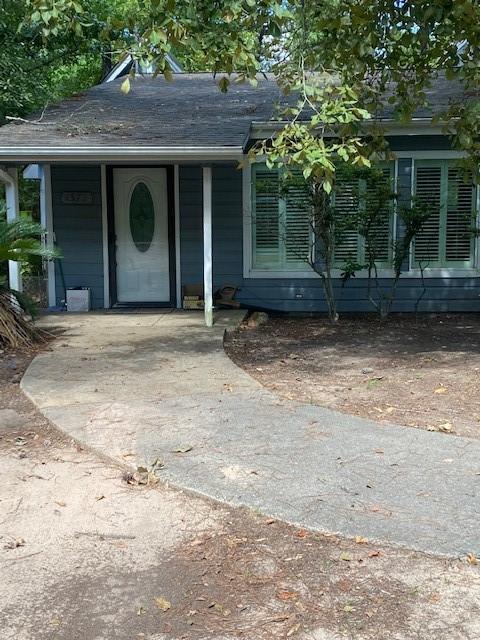 entrance to property featuring roof with shingles