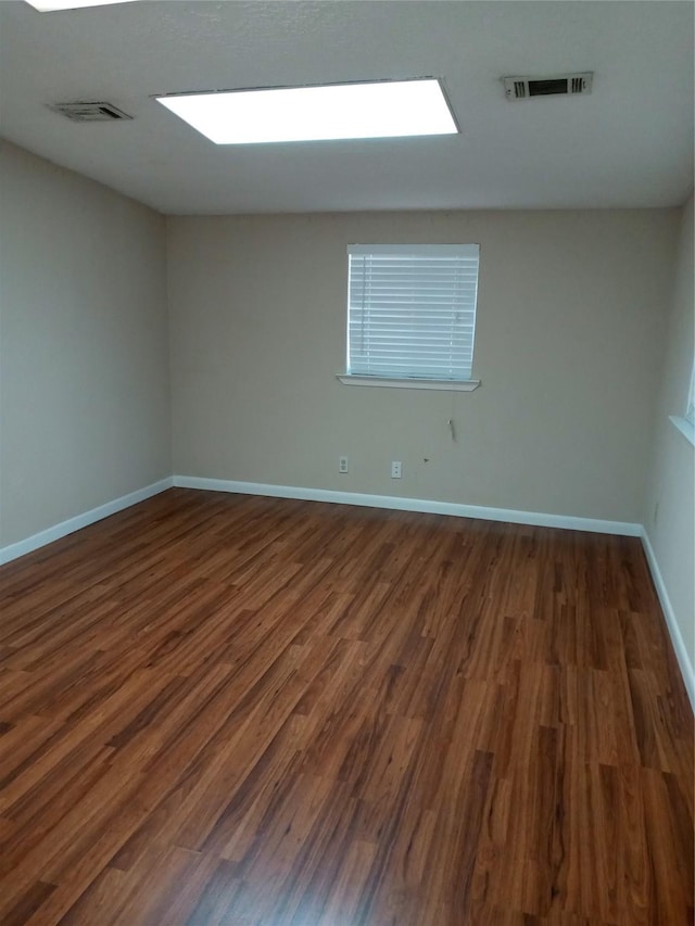 unfurnished room with dark wood finished floors, baseboards, and visible vents