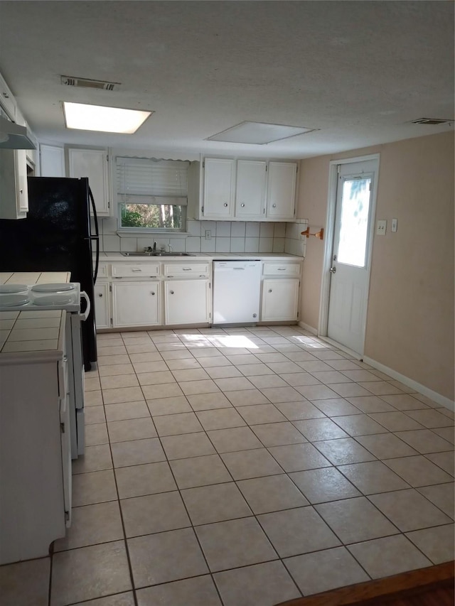 1372 Apache Dr, Montgomery, TX 77316 - kitchen with dishwasher, tile countertops, light tile patterned floors, white cabinetry, and range