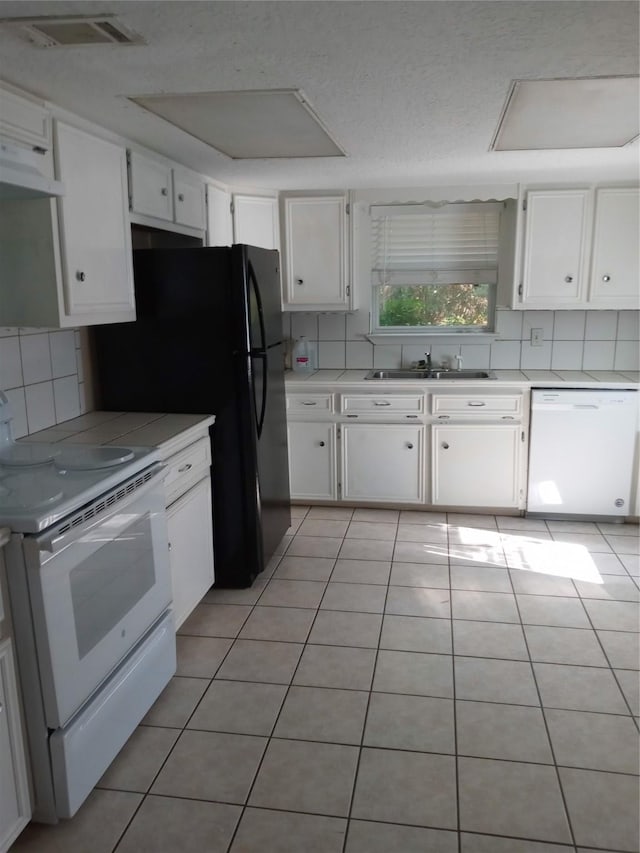 1372 Apache Dr, Montgomery, TX 77316 - kitchen featuring white appliances, tasteful backsplash, white cabinetry, light tile patterned floors, and under cabinet range hood