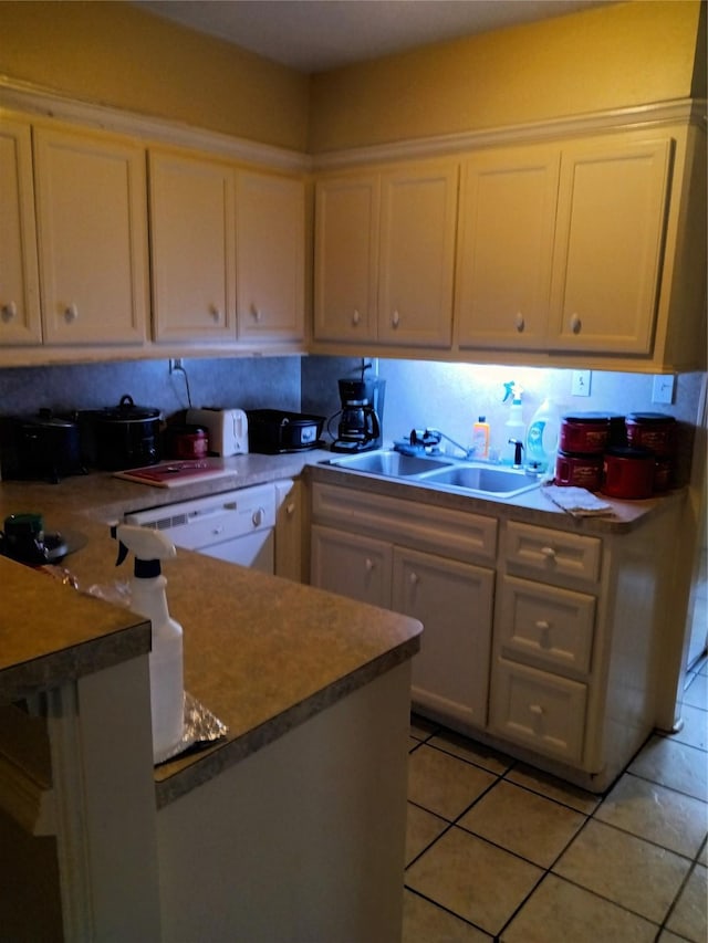 kitchen with light tile patterned flooring, a sink, white cabinetry, a peninsula, and white dishwasher