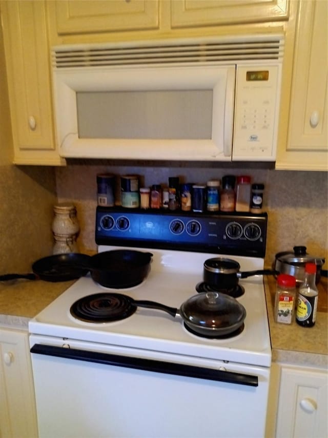 kitchen with white appliances, white cabinetry, light countertops, and decorative backsplash