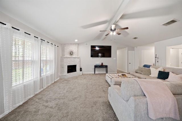 carpeted living area with a brick fireplace, visible vents, a ceiling fan, and lofted ceiling with beams