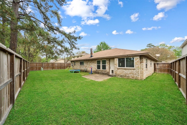 back of house featuring a trampoline, a fenced backyard, brick siding, and a patio