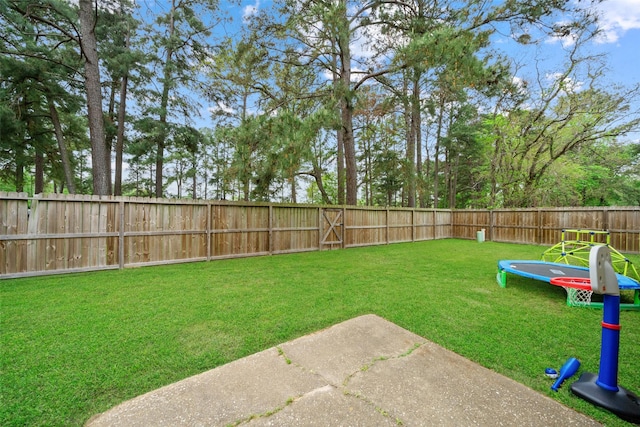 view of yard with a trampoline and a fenced backyard