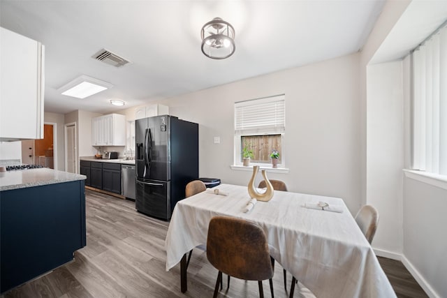 dining room featuring light wood-type flooring, baseboards, and visible vents