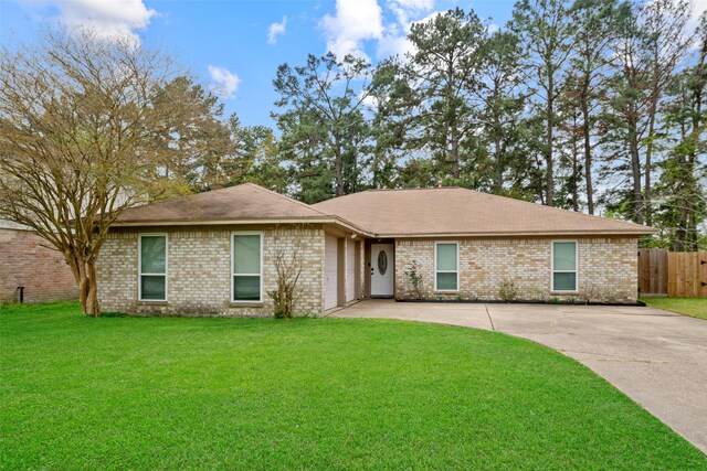ranch-style house with driveway, brick siding, fence, and a front yard
