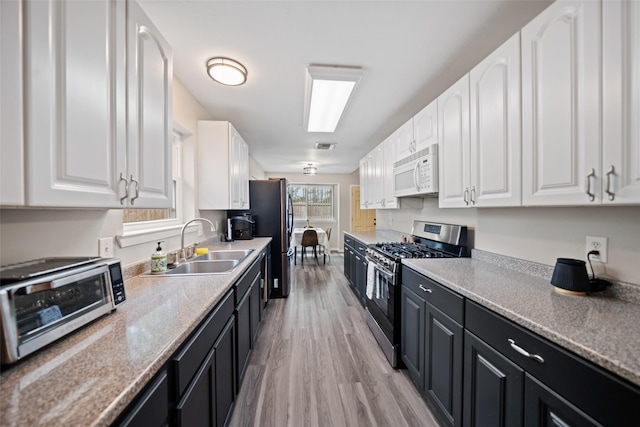 kitchen featuring white cabinets, a sink, stainless steel appliances, and dark cabinets