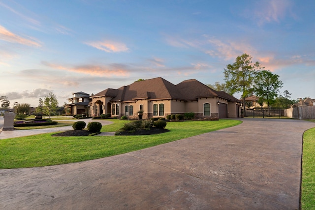 34 New Oak Trl, Humble, TX 77346 - french country style house featuring fence, an attached garage, stucco siding, a front lawn, and curved driveway