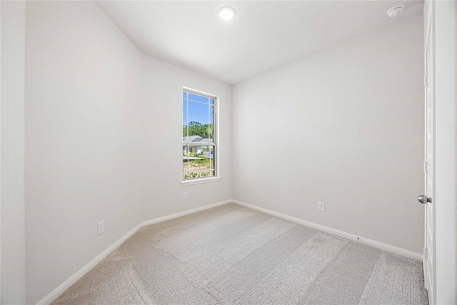 unfurnished room with light colored carpet and baseboards