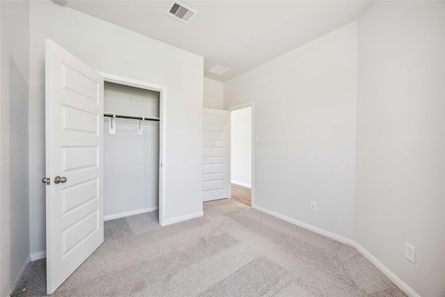 unfurnished bedroom with a closet, visible vents, carpet, and baseboards