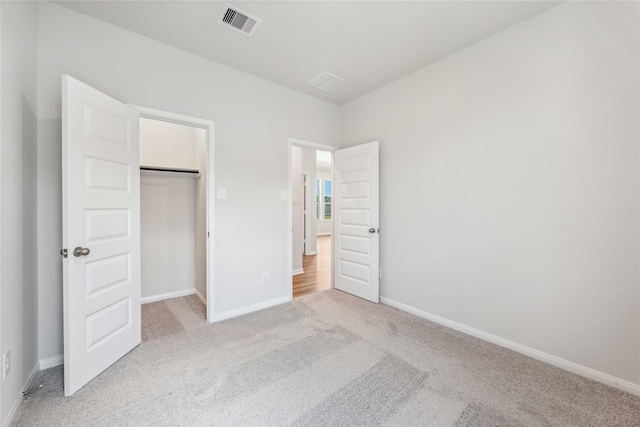unfurnished bedroom featuring a closet, visible vents, light carpet, and baseboards