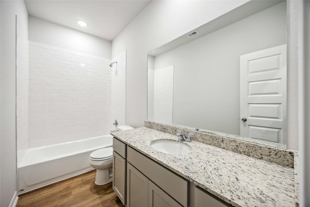 bathroom featuring visible vents, toilet, shower / bath combination, wood finished floors, and vanity