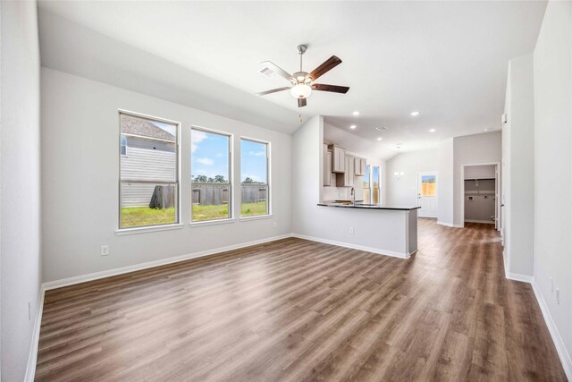unfurnished living room with lofted ceiling, a sink, recessed lighting, wood finished floors, and a ceiling fan
