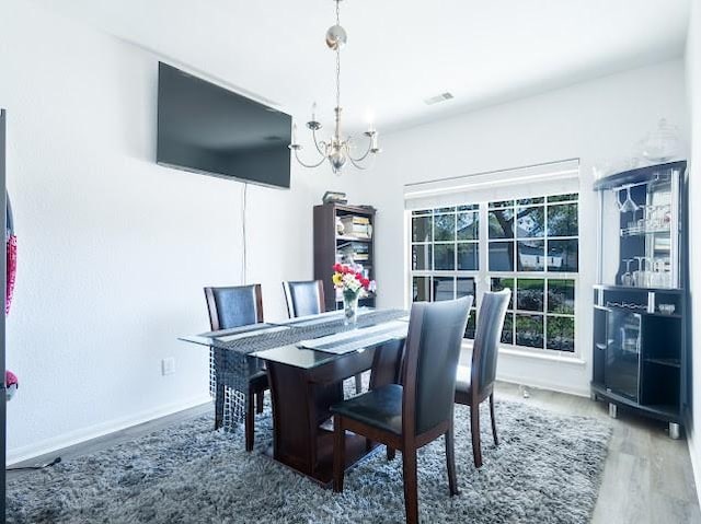 dining space featuring baseboards, wood finished floors, and a chandelier