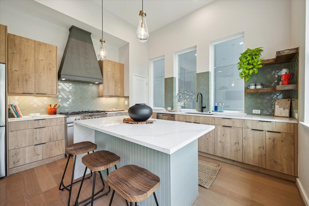 3905 Yale Heights Dr, Houston, TX 77018 - kitchen featuring custom exhaust hood, appliances with stainless steel finishes, light brown cabinets, a sink, and a kitchen breakfast bar