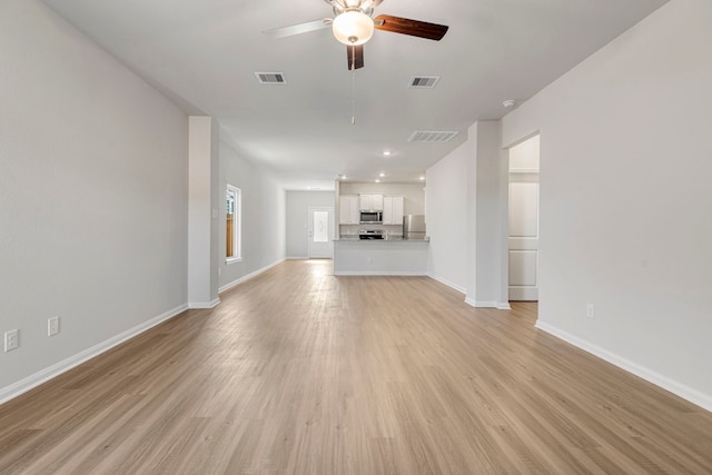 unfurnished living room with light wood finished floors, a ceiling fan, visible vents, and baseboards