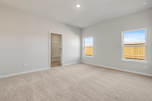 spare room featuring light colored carpet, recessed lighting, and baseboards