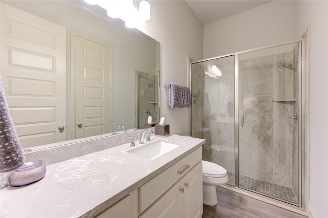 bathroom featuring a stall shower, wood finished floors, toilet, and vanity