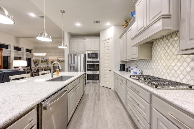 kitchen featuring light countertops, stainless steel appliances, tasteful backsplash, a sink, and ventilation hood
