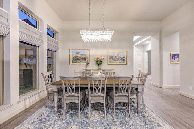 dining space with baseboards, a notable chandelier, and wood finished floors