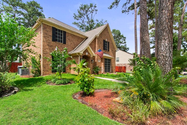 traditional home with fence, a front yard, and brick siding
