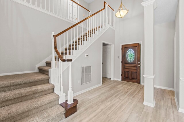 foyer entrance with a high ceiling, visible vents, baseboards, and stairway
