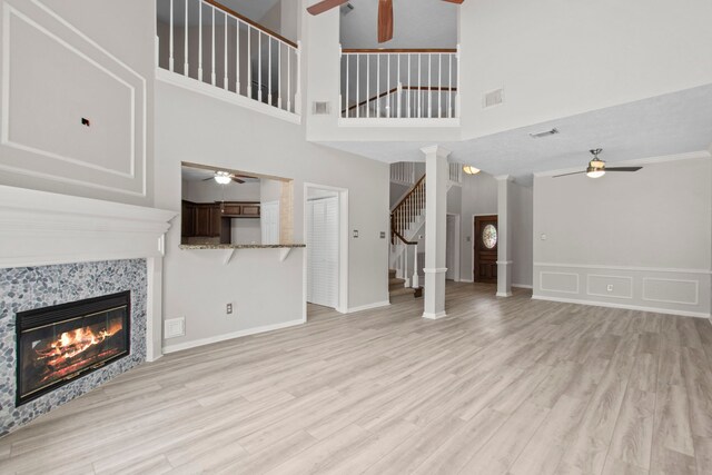 unfurnished living room with ceiling fan, wood finished floors, stairway, and a tile fireplace