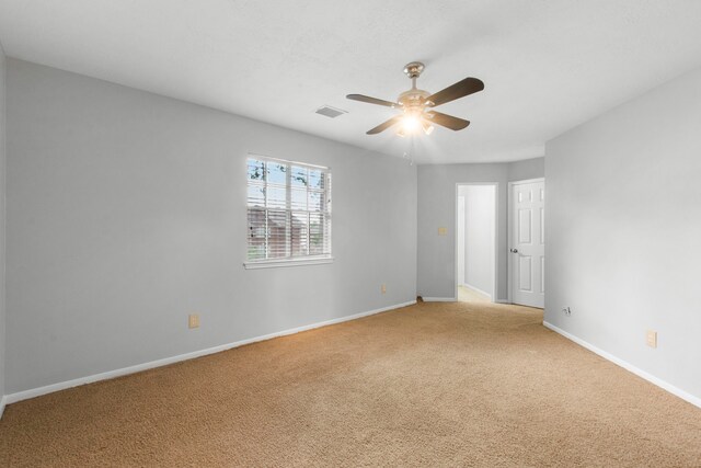 spare room with ceiling fan, visible vents, light carpet, and baseboards