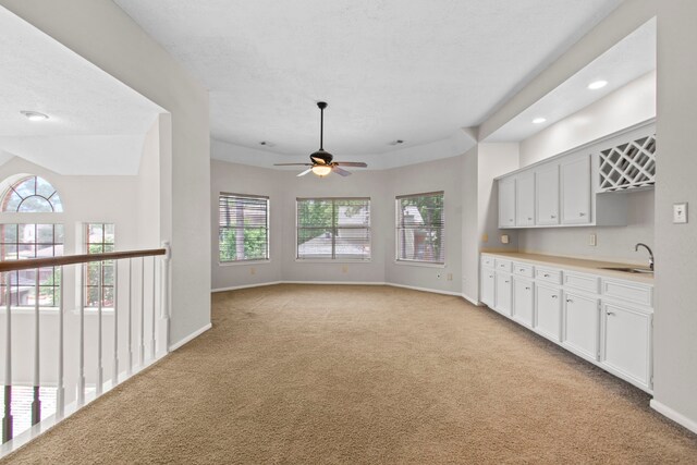 interior space with a sink, light carpet, baseboards, recessed lighting, and a ceiling fan