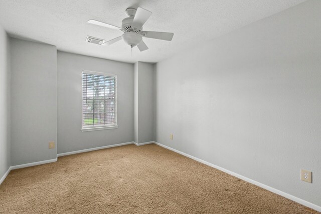 carpeted empty room with a ceiling fan, baseboards, visible vents, and a textured ceiling