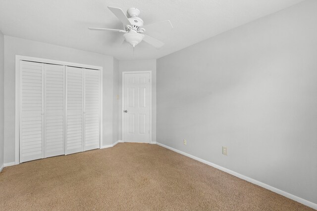 unfurnished bedroom featuring baseboards, a ceiling fan, carpet, and a closet